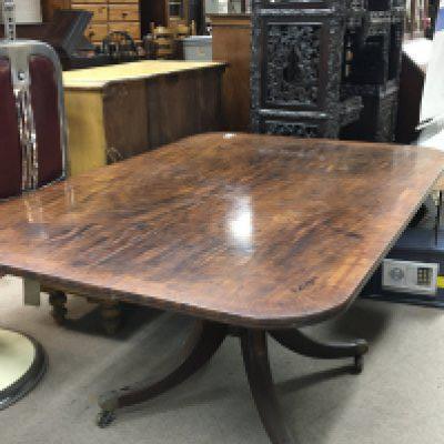 A George III mahogany tip action dining table with a cross-banded edge on splayed inlaid legs terminating in brass cap and caster 148cmx100cm