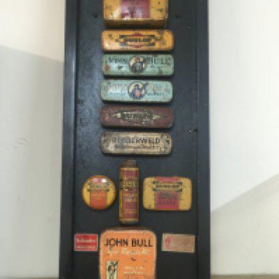 A framed display of vintage bike puncture repair tins. Postage category C