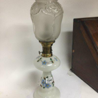 A glass oil lamp painted with flowers the shade with Art nouveau influences.