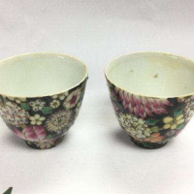 A pair of rice wine cupswith elaborate floral decoration on a black ground, six character marks to base, approx height 6.5cm. Shipping category D.