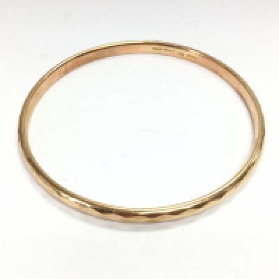 A 9ct gold metal core bangle. 27g and 8cm diameter. Postage A