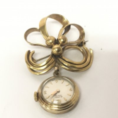 A gold cased ladies watch set on an open simulated ribbon gold plated brooch and a gold bar brooch