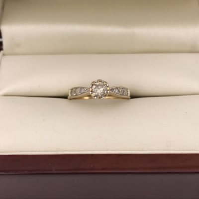 An 18ct yellow gold diamond solitaire ring with diamonds set in the shoulders. Approx weight 2.15 grams, approx size L1/2.