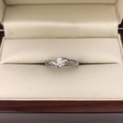 An 18ct white gold diamond set solitaire ring with diamonds set in the shoulders.