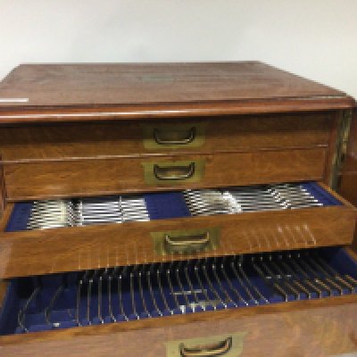 A Quality Mappin & Webb canteen of silver cutlery in a well fitted oak cabinet with four drawers with unset brass handles each compartment containing predominantly matching silver cutlery with some steel knifes and extra silver and silver plated cutlery.