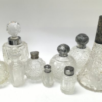 A Collection of cut glass perfume bottles with silver collars and tops. This lot cannot be posted