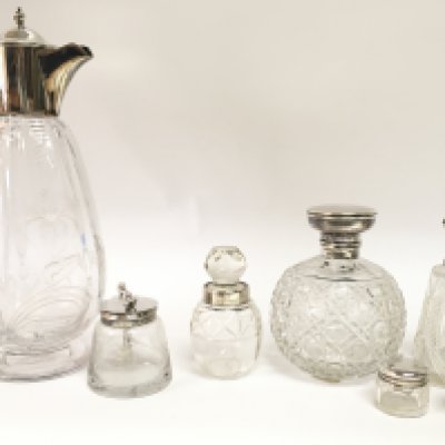 A collection of cut glass silver hallmarked bottles including an early 20th century claret jug with engraved floral design. This lot cannot be posted