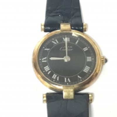 A ladies Cartier Argent watch 925 with gold plating with a black dial and silvered Roman numerals blue sapphire adjustment crown Quartz movement. Serial number 18 026687 Replacement strap not seen working.