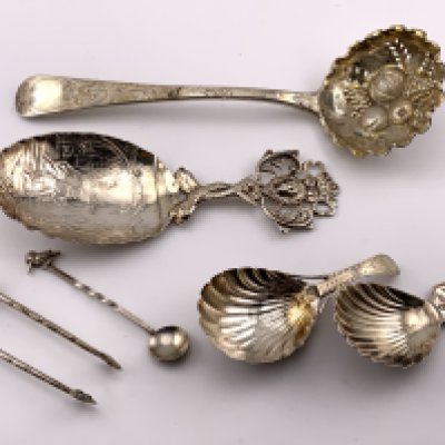 A small collection of hallmarked silver cutlery to include a Paul Storr berry spoon, A sterling silver Dutch caddy spoon, 2 Georgian silver shell bowl caddy spoons, A pair of Japanese style silver sugar nips, sterling silver salt spoon. (A)