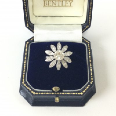 An 18ct white gold diamond set flower style ring, set with a large centre stone surrounded by petals set with singular stones. Approx weight 7.06 grams, size L.