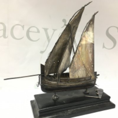 A hallmarked silver model boat (approximately 19.5cm tall including stand). In need of restoration Postage category B