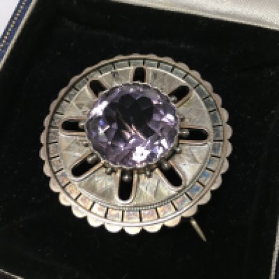 A silver brooch with a large central amethyst