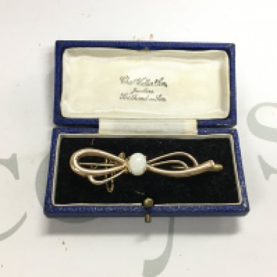 A 9ct gold bow shaped brooch set with an opal. Approx weight 5.50 grams.
