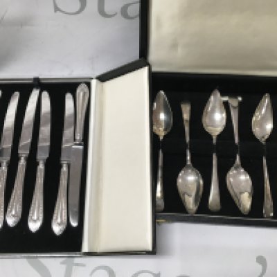 A cased set of silver grapefruit spoons And a set of silver handle butter knifes .
