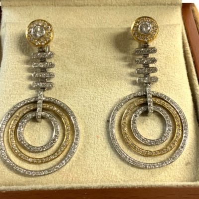 A pair of 18ct yellow and white gold drop earrings each stud section set with a 0.33ct solitare diamond surrounded by small 0.01ct stones, the drop section in white gold also inset with cut stones finished by 3 concentric rings each encrusted with small cut stones. Purchased at Gomez & Molina, Joyeros, Spain. (A)
