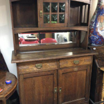 An arts and crafts dresser with raised cupboards, green stained glass, brass fittings. Dimensions 52x120x184cm