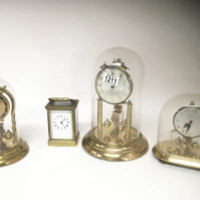 A brass cased carriage clock and three brass anniversary clocks under a glass dome. (4)
