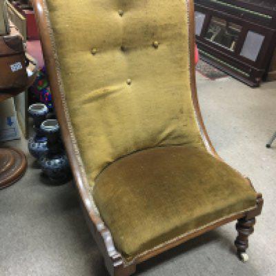 A wide seated Victorian chair on turned legs with an upholstered back and seat.
