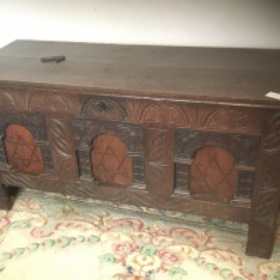 An 18th century oak trunk with a hinged top above panels inlaid with a star pattern.