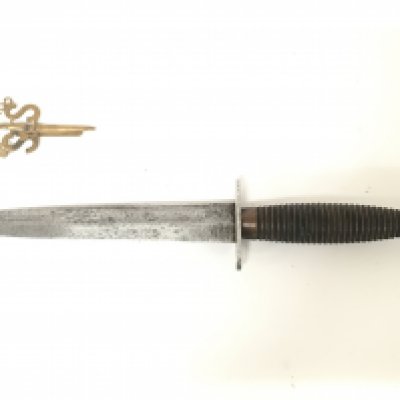 A Fairbairn Sykes design commando knife and a vintage cap badge. This lot cannot be posted
