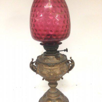 A Victorian gold painted spelter oil lamp with a cranberry glass shade (cracked)