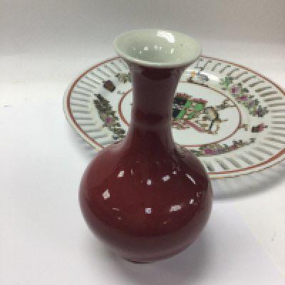 A small Chinese Sang De Boeuf vase together with an armorial plate .