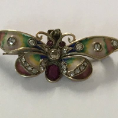A pendant in the form of a butterfly the wings with coloured enamel inset with diamonds and rubies.