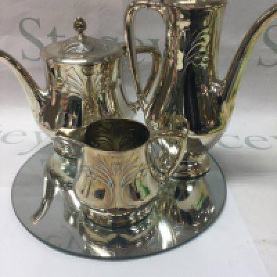 A WMF three piece tea set tea pot hot water pot milk jug having Art nouveau influence on a circle mirror base .