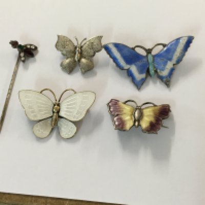 A collection of four silver and enamel brooches in the form of butterflies. And a stick pin .