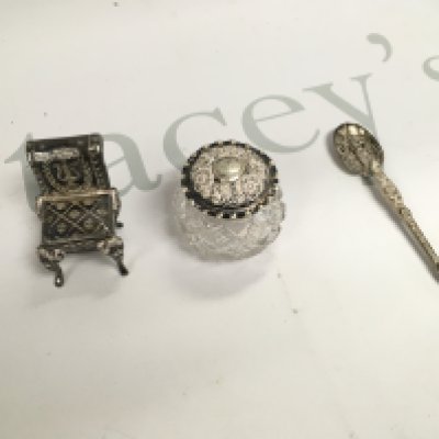 A small collection of silver including a miniature chair a spoon and a jar.
