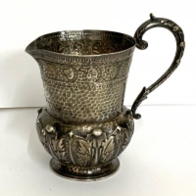 A small hallmarked silver jug with acanthus leaf decoration and hammered decoration. marks for London, 1900 Goldsmith alliance marks S.S (12cm) (A).