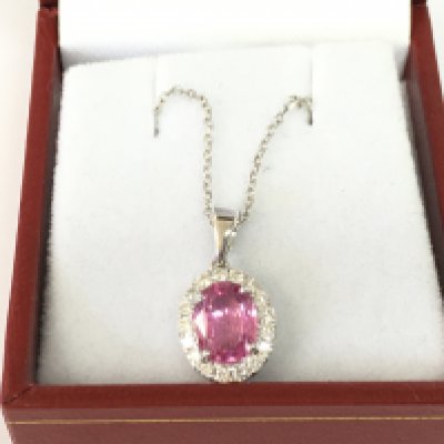An 18ct white gold oval pink sapphire and RBC diamond cluster pendant on an 18ct whote gold chain. Pink sapphire 1.47ct and 0.27ct diamonds.