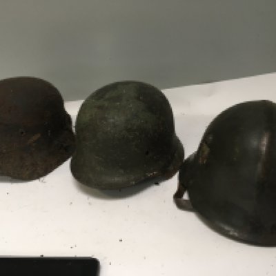 An interesting German steel combat helmet with worn single side decal and a ribbed top original leather lined and a rediscovered dig find Luftwaffe helmet distressed battle condition and one other M42 helmet (3)