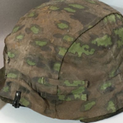 A German Third Reich II world war steel helmet M35 pattern with green camouflage double sided cover the helmet with no liner and areas of rust and wear particularly to the edges.