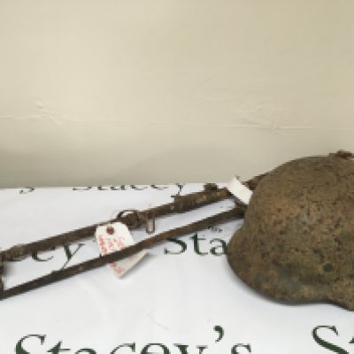 A I world war rediscovered relic retrieved from the ground on the Somme battle field possible an Enfield 303 rifle with bayonet. Also a German II world war Third Reich SS battle helmet with traces of a single decal the helmet with shrapnel damage.