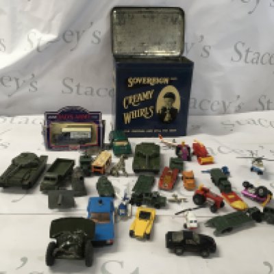 A collection of Playworn diecast and plastic model vehicles including some military items including a vintage tinplate twin barrelled artillery gun made in Japan. The collection comes in an old shop tin advertising Cream Whirls toffees in nice condition. No reserve