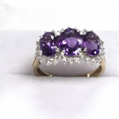 9ct yellow and white gold three stone graduated amethyst and diamond trilogy ring, boxed. Amethyst&rsquo;s 1.50ct Approx. Diamonds 0.30ct Approx. Postage category A. Ring size Approx N.
