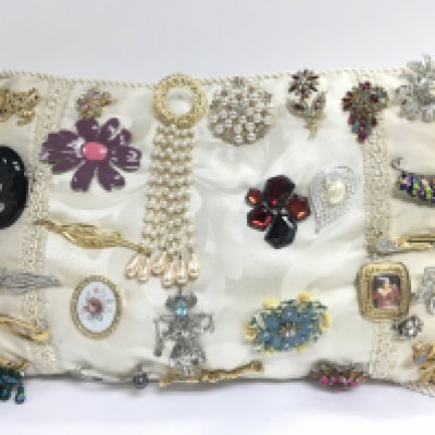 a collection of brooches on a cushion. Postage category B