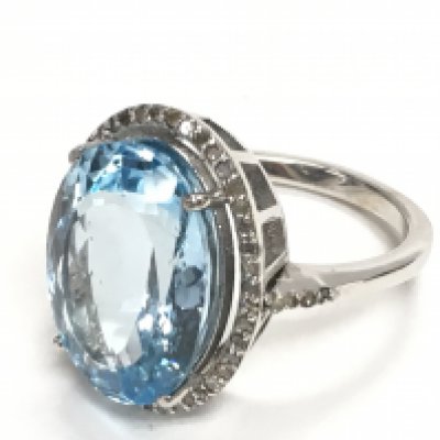 Oval dress ring in silver set with large oval blue topaz and a halo of R/C diamonds with a diamond set shoulders. Topaz 11.45ct. Diamonds 0.35ct. Postage category A. Ring size Approx K/L.