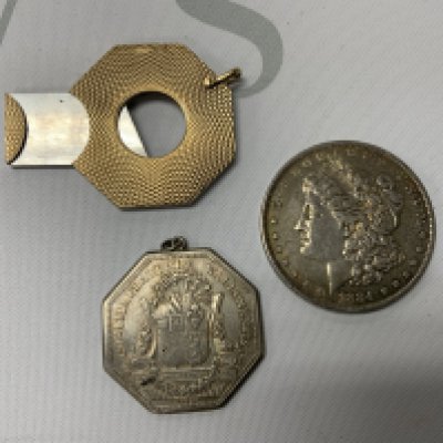 A 9ct gold engine turned cigar cutter together with a 1884 New Orleans Silver Morgan Head Dollar, French Jetton (Pendant). (A)