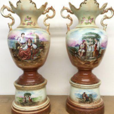 A pair of Victorian vases decorated with hand painted panels of classic scenes and pink rose designs , gilt detailing and handles, open tops and pedestal bases. 56cm tall approximate total height. This lot cannot be posted