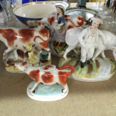 A collection of four Staffordshire figures cows and figures including a creamer .