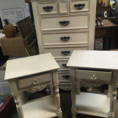 A white painted chest of drawers and a pair of white painted conforming bedside tables