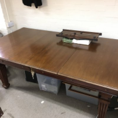 An early 20th century mahogany rising top snooker dining table with balls, cues and a scoreboard . 103cm wide 194cm long 75cm tall.