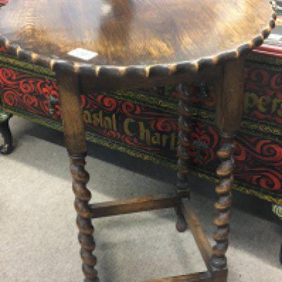 An oak occasional table the shaped top on barley twist legs.