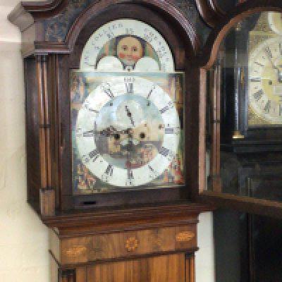 An elaborate Mahogany George III long case clock the inlaid case with fluted pilasters with an arches swan neck pediment with a painted dial and moon roller eight day going with weights and pendulum.