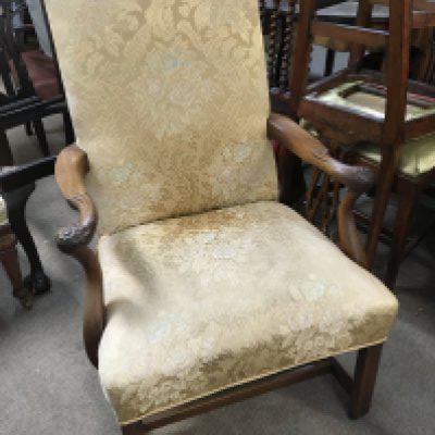 A George III Mahogany open arm chair with an upholstered seat and back with carved open arms with floral motifs on square legs united by stretches.