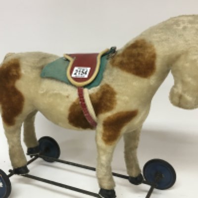 A Vintage pull along horse with pull cord and red saddle.