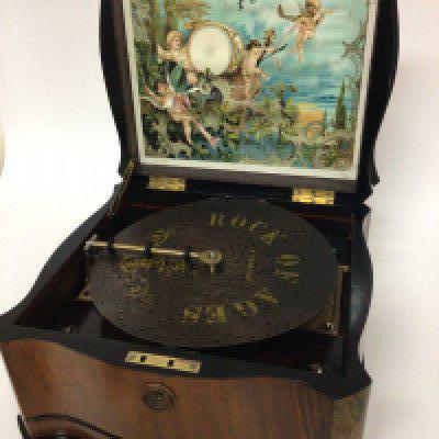 A late 19th century Continental walnut cased Polyphon in very good condition the shaped case with a hinged lid enclosing a coloured lithograph with musical cherubs. The movement a style 41 lever wound 20cm discs seen working and with additional discs.