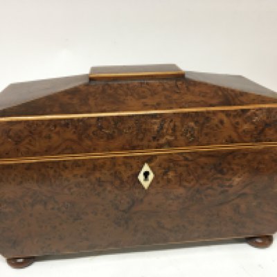 A burr walnut tea caddy with a shaped top and inverted sides with a well fitted interior with mixing bowl the sides with wooden ring handles. Length 35cm